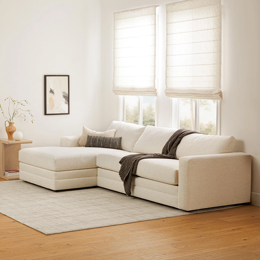 Modern beige sectional sofa with chaise in minimalist living room with natural light and neutral decor