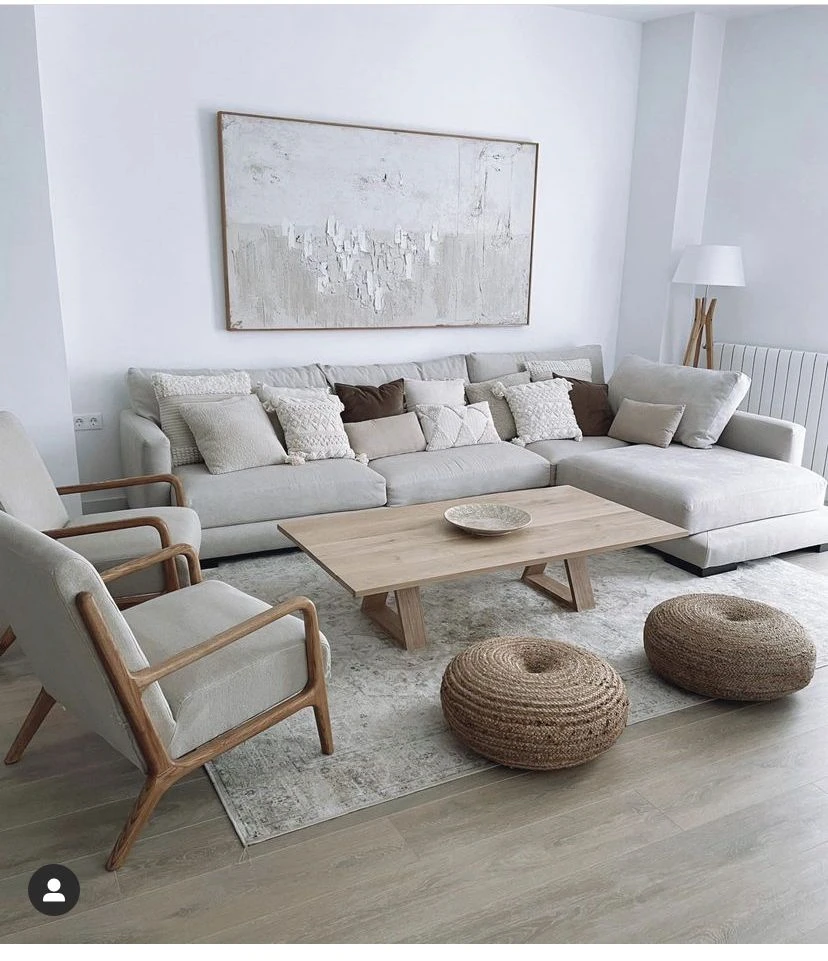 Minimalist living room with neutral tones, gray sectional sofa, wooden coffee table, and natural woven poufs