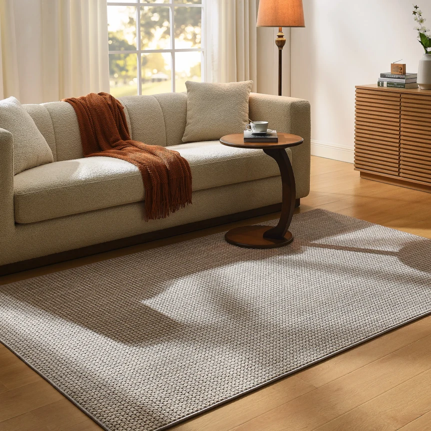 Modern geometric area rug in gray and white tones anchoring living room with cream sofa and wooden furniture