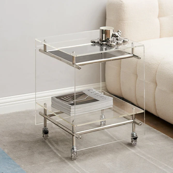 Modern acrylic side table with two shelves and chrome accents next to beige sofa in contemporary living room