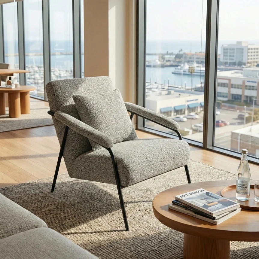 Modern gray accent chair with metal frame beside round wooden side table in bright living room with city views