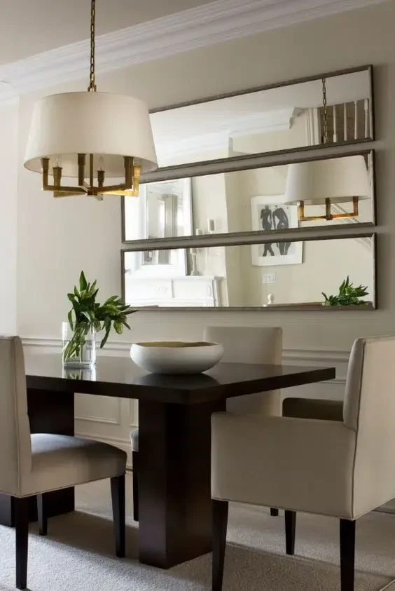 small dining room with a large mirror on one wall reflecting the pendant light and table setting