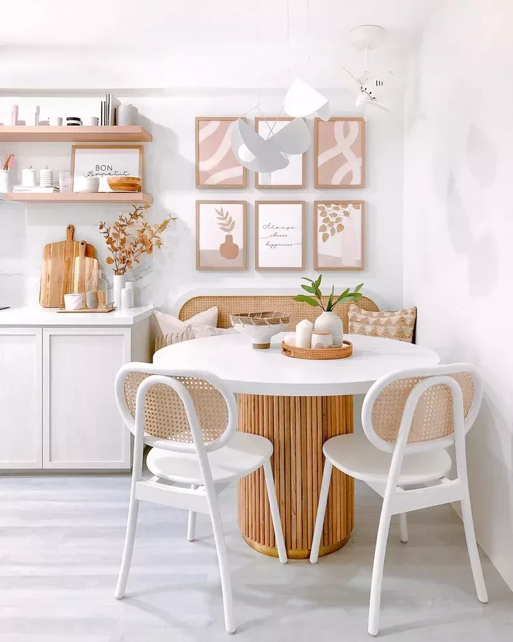 Cozy small dining room with round white table, wooden base, white chairs, and gallery wall art