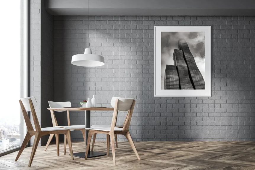 Modern dining room with gray brick wall, white pendant light, wooden chairs, and monochrome wall art