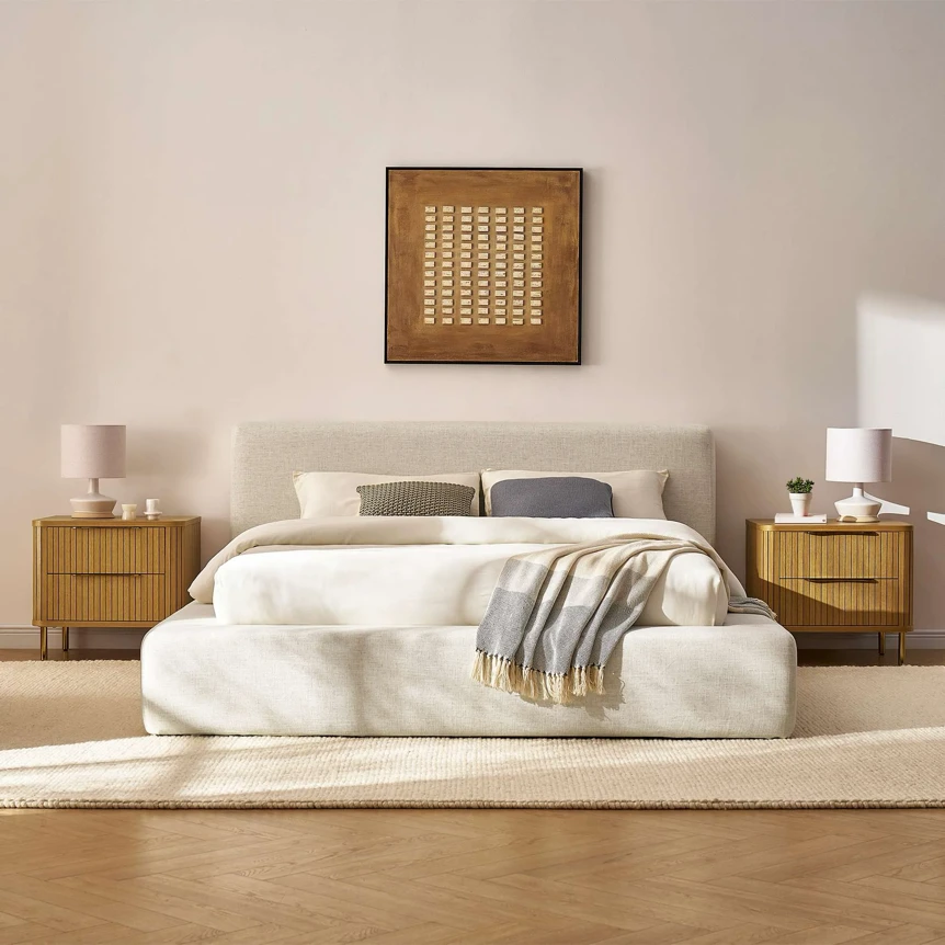 Modern bedroom with white upholstered bed, wooden nightstands, and minimalist wall art in neutral tones