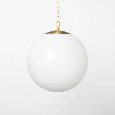 Milk glass globe ceiling pendant light with brass hardware and chain suspension on white background
