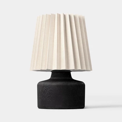 Mini table lamp with black wooden base and white pleated fabric shade on neutral background