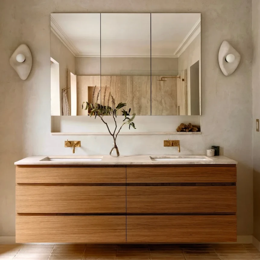 Modern bathroom with floating wooden vanity ceramic sconces and natural terracotta tile floor