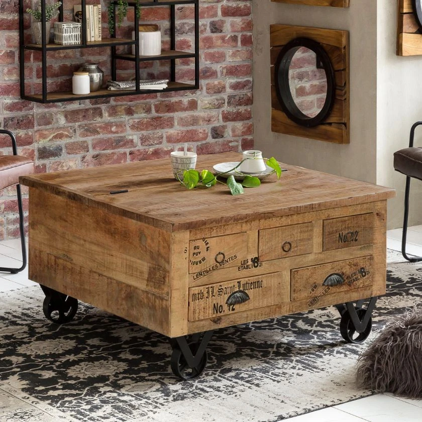 Rustic wooden coffee table with drawers and industrial metal wheels on patterned rug in brick-walled living room
