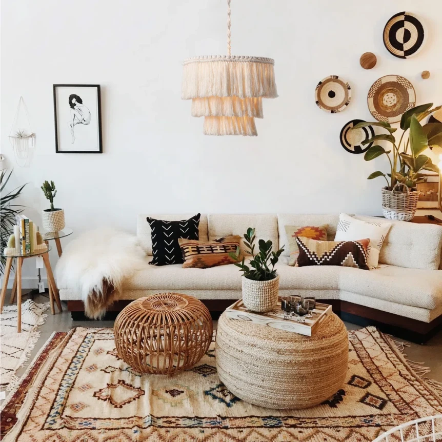 Boho living room with white sofa, rattan ottoman, tiered chandelier, and natural wood accents on patterned rug
