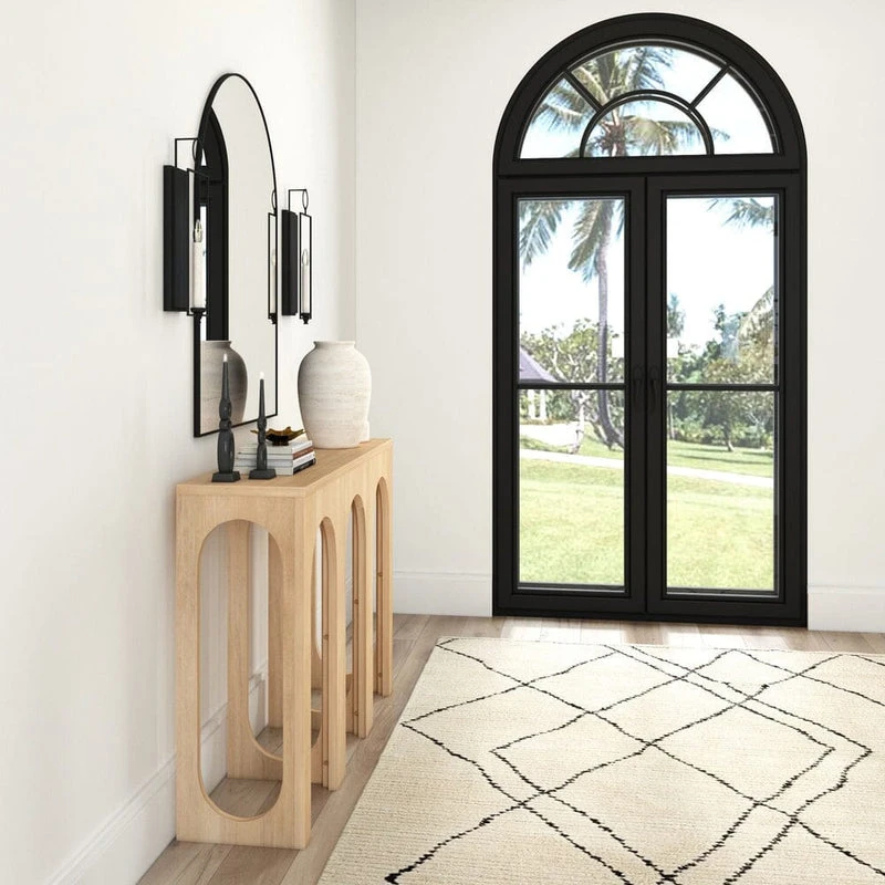 Modern entryway with wooden console table, black arched door, geometric rug, and wall sconces