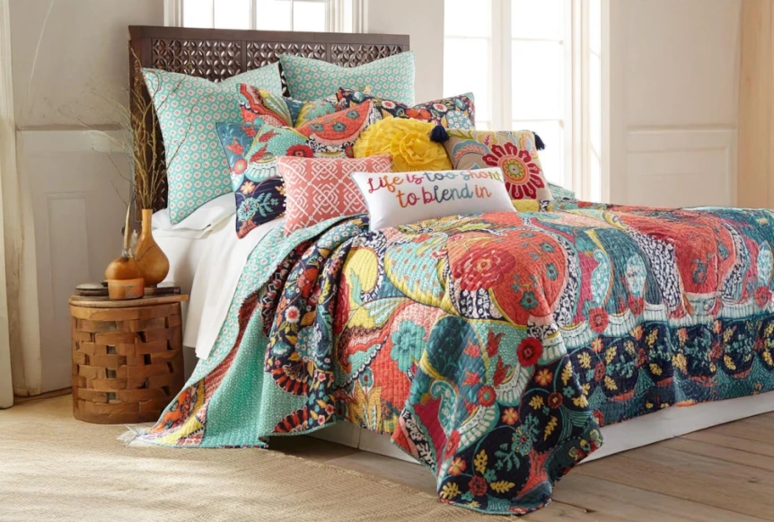 Colorful bohemian bedding with patchwork quilt, decorative pillows, and turquoise accents in cozy bedroom setting