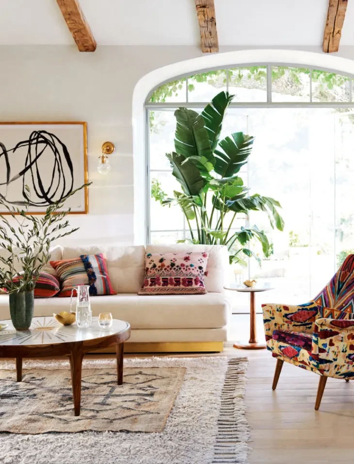 Bright boho living room with arched window, large tropical plant, patterned chair, and Moroccan rug