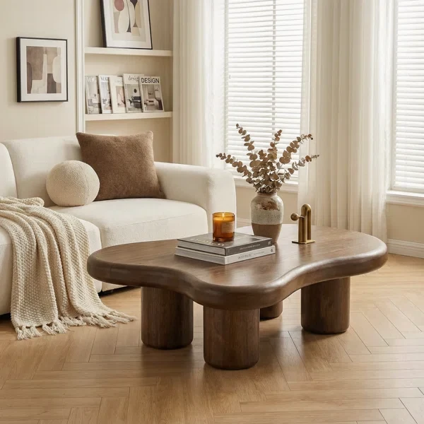 Modern wooden coffee table with curved edges in neutral living room with beige sofa and natural decor