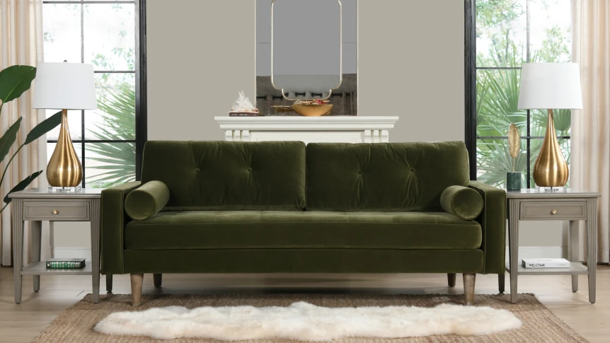 Green velvet mid-century modern sofa with wooden legs in contemporary living room with neutral decor