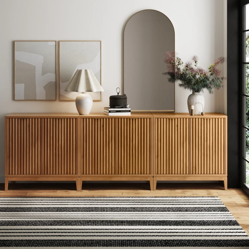 Mid-century modern wooden credenza with vertical slat doors on black legs with striped rug and neutral decor