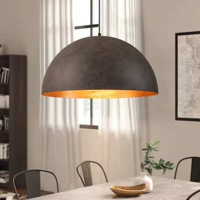 Large black dome pendant light with copper interior hanging over dining table in industrial kitchen