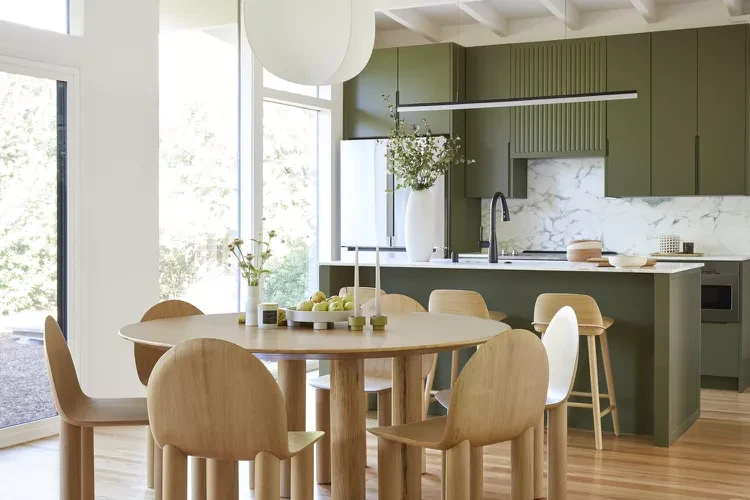 Japandi kitchen and dining room with wooden table, beige chairs, and olive green cabinets with linear lighting