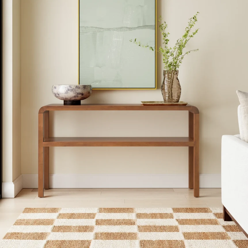 Minimalist wooden console table with mirror and vase in modern entryway with striped jute rug