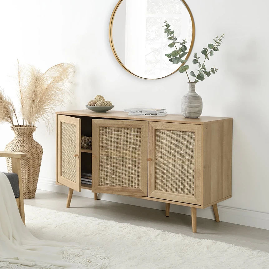 Mid-century modern wooden sideboard with rattan door panels in light oak finish styled with mirror and vase