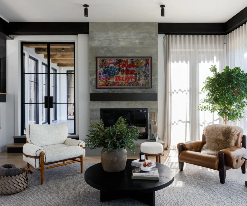 Modern industrial living room with concrete fireplace, leather chairs, black round coffee table and steel-framed windows