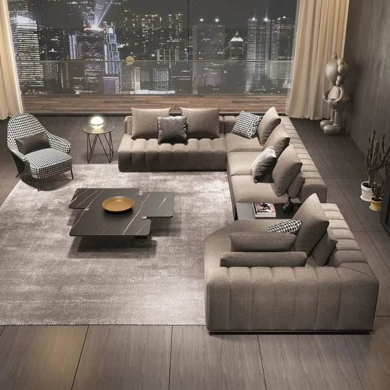 Modern L-shaped sectional sofa in gray fabric with coffee table on plush rug in contemporary living room with city views