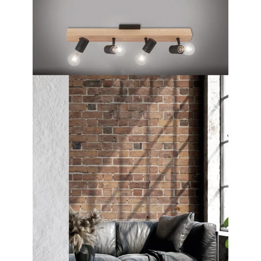 Industrial wooden track lighting fixture with adjustable black spotlights mounted on exposed brick wall above gray sofa
