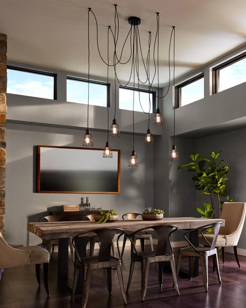 Modern dining room with industrial pendant lights, wooden table, and high ceilings with large windows