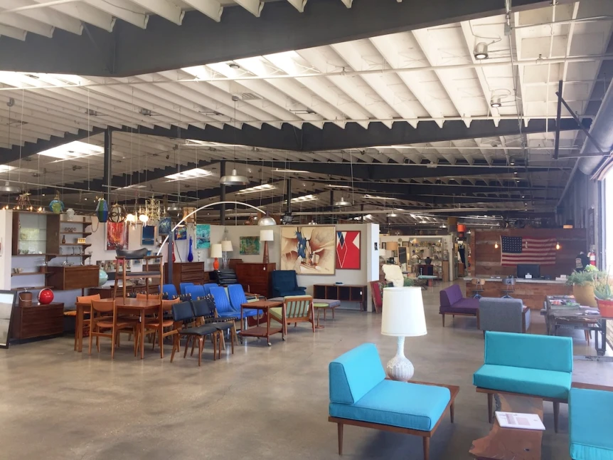 Modern Scandinavian style office with light wood furniture, blue seating, and exposed ceiling beams