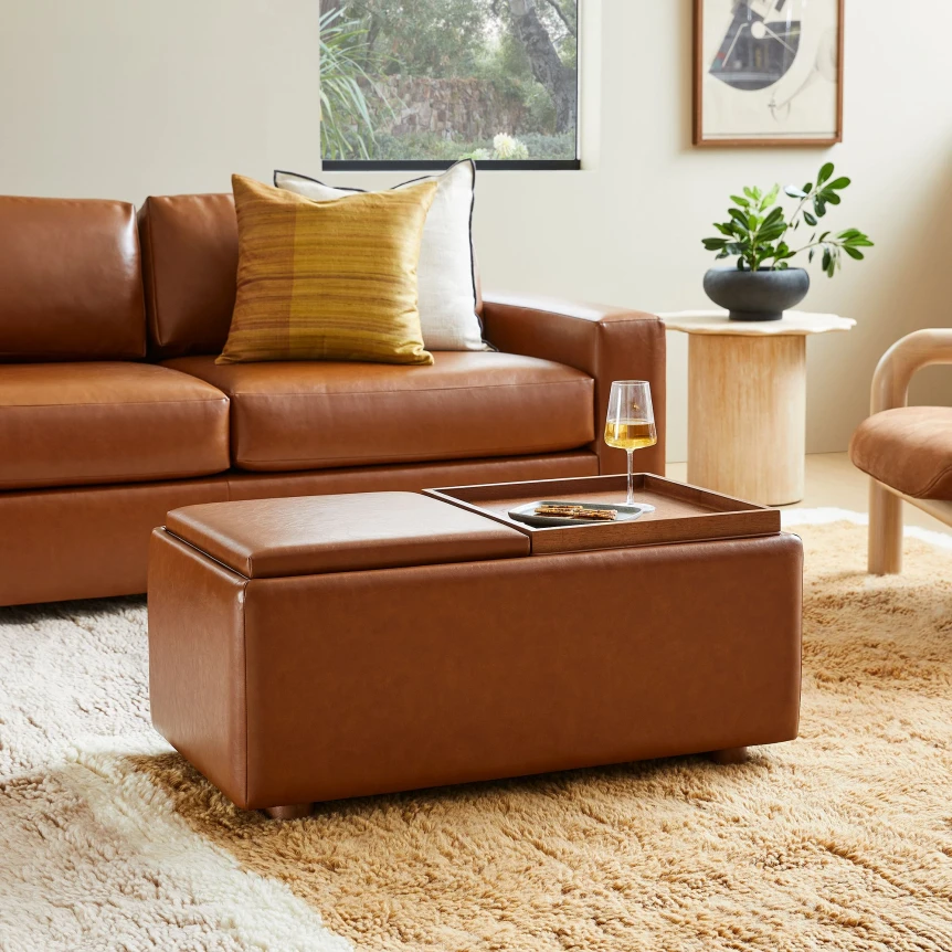 Modern brown leather storage ottoman with tray top in contemporary living room with tan sofa and natural decor