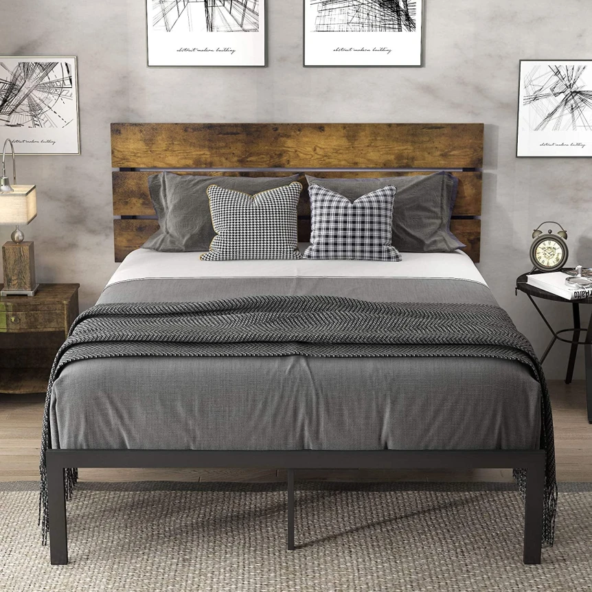 Industrial metal bed frame with wooden headboard and gray bedding in modern bedroom with artwork