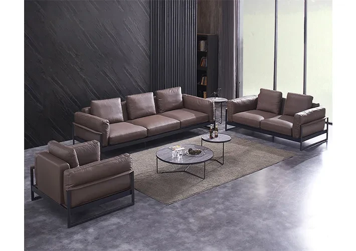 Modern brown leather sofa set with metal accents in industrial living room with concrete floors and dark walls