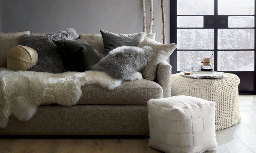 Scandinavian living room with gray sofa, sheepskin throws, and minimalist decor in neutral tones