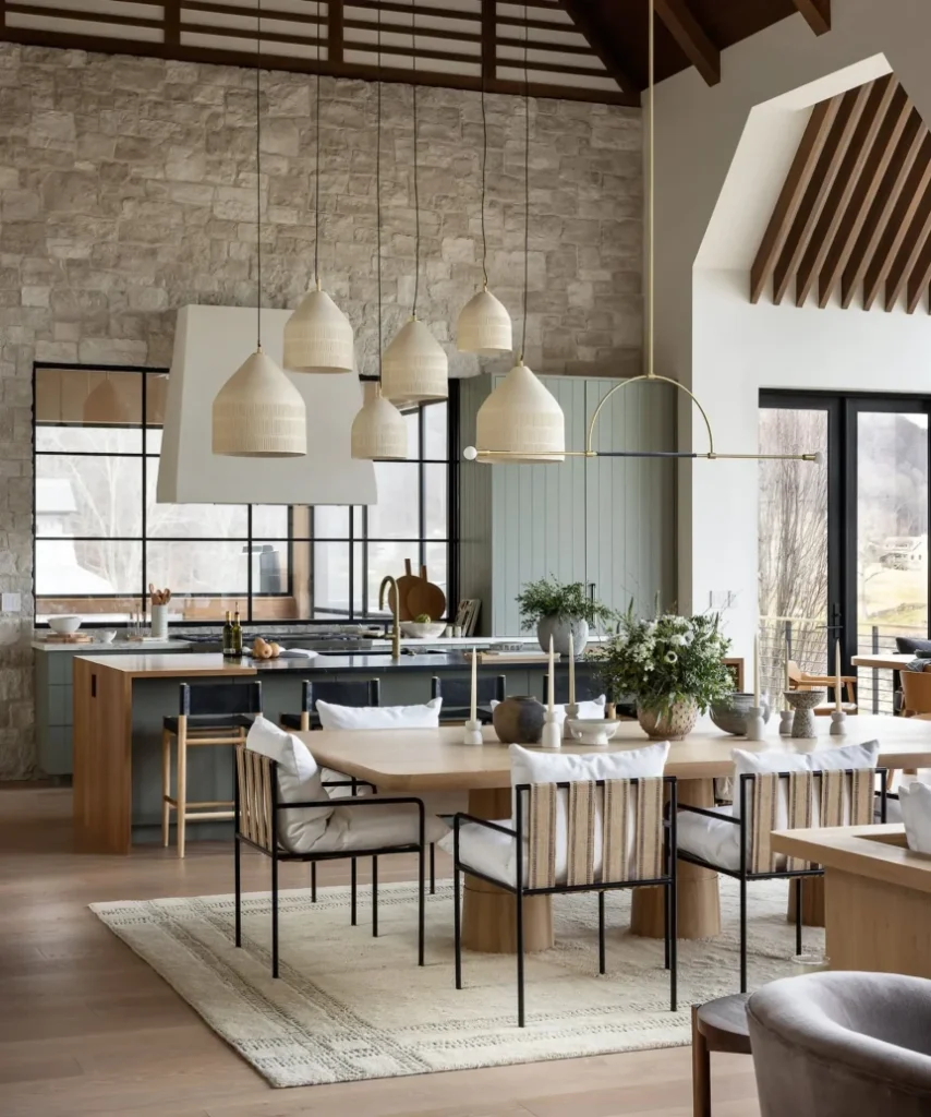 Modern Scandinavian kitchen with pendant lights, wooden dining table, minimalist chairs, and exposed concrete walls