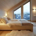 Minimalist Scandinavian bedroom with wooden floors, white bedding, sloped ceiling, and mountain view window
