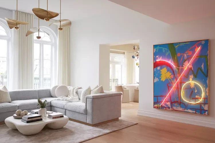Modern living room with white sofa, wooden coffee table, and vibrant abstract art on pink-accented walls