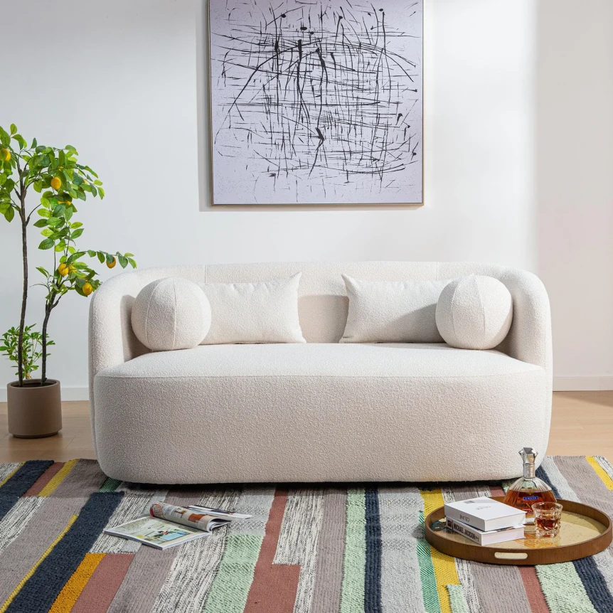 Modern curved white boucle sofa with rounded pillows on colorful geometric rug in bright living room