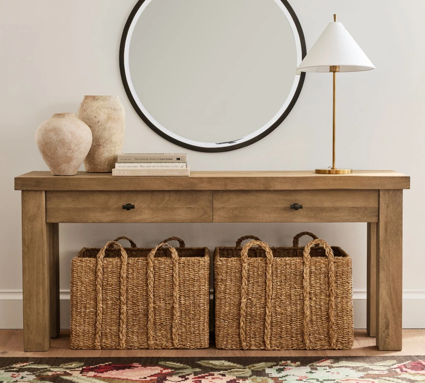Rustic wooden console table with wicker baskets, decorative mirror, and lamp in modern farmhouse entryway
