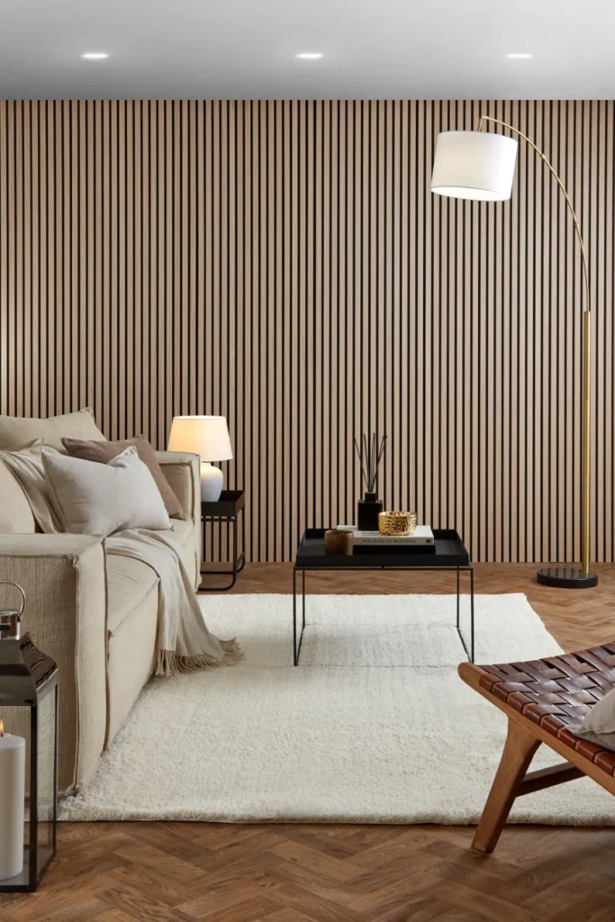 Scandinavian living room with vertical wood slat wall, beige sofa, white rug, and minimalist decor