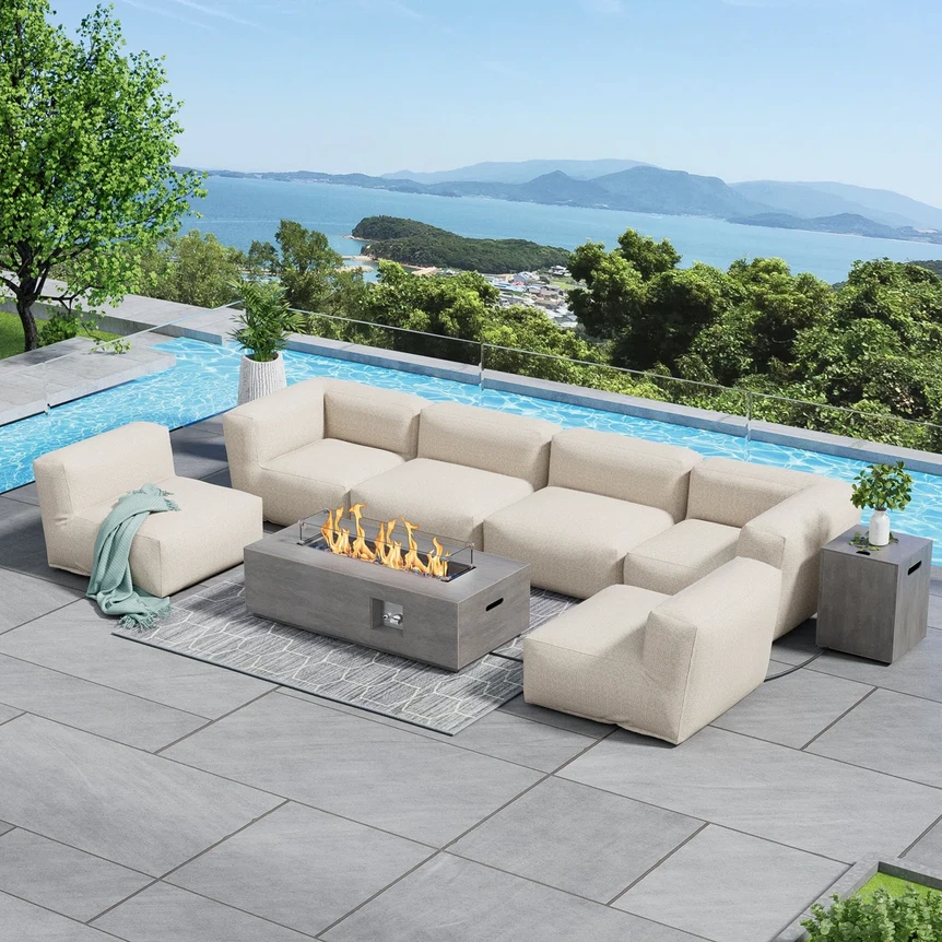 Large beige sectional sofa with fire pit table on patio overlooking pool and ocean view