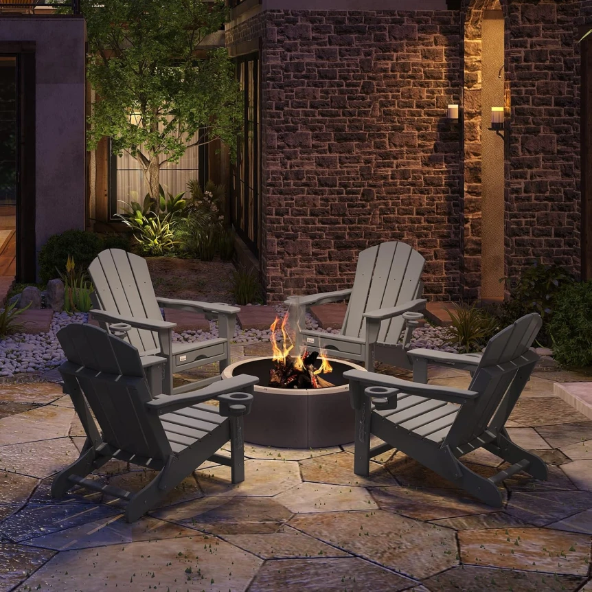 Outdoor fire pit surrounded by Adirondack chairs on patio with brick wall and evening lighting