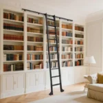 Floor-to-ceiling white built-in bookshelves with rolling ladder filled with colorful book collection