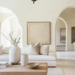 Neutral living room with beige walls, white sectional sofa, wooden coffee table, and arched doorways