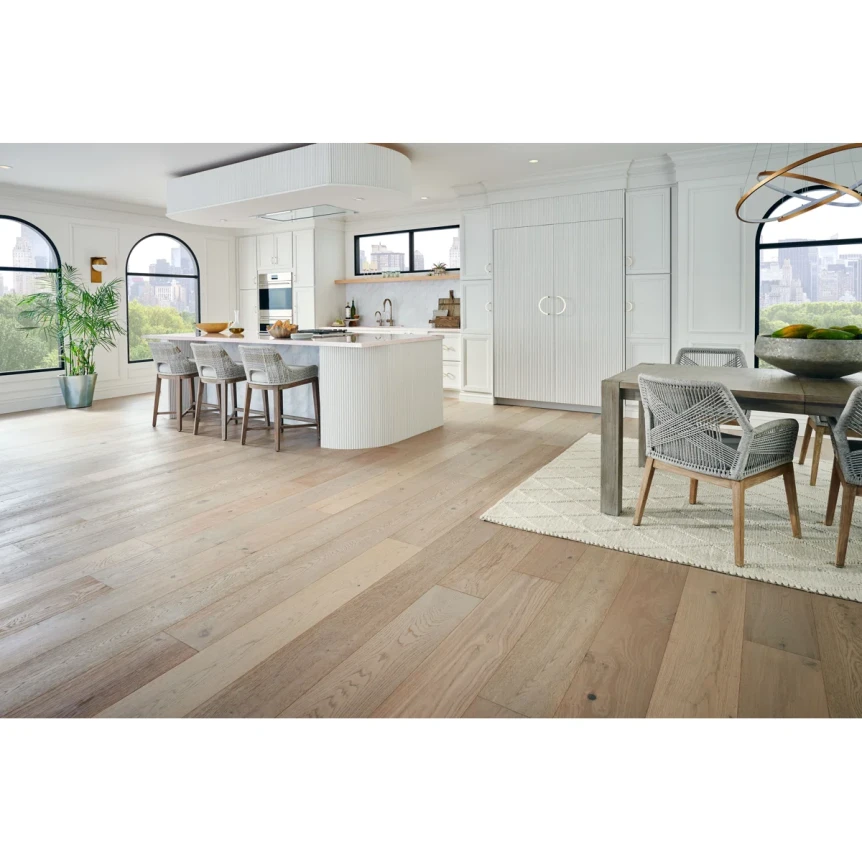 Light wood flooring in open concept kitchen and dining room with white walls and large arched windows