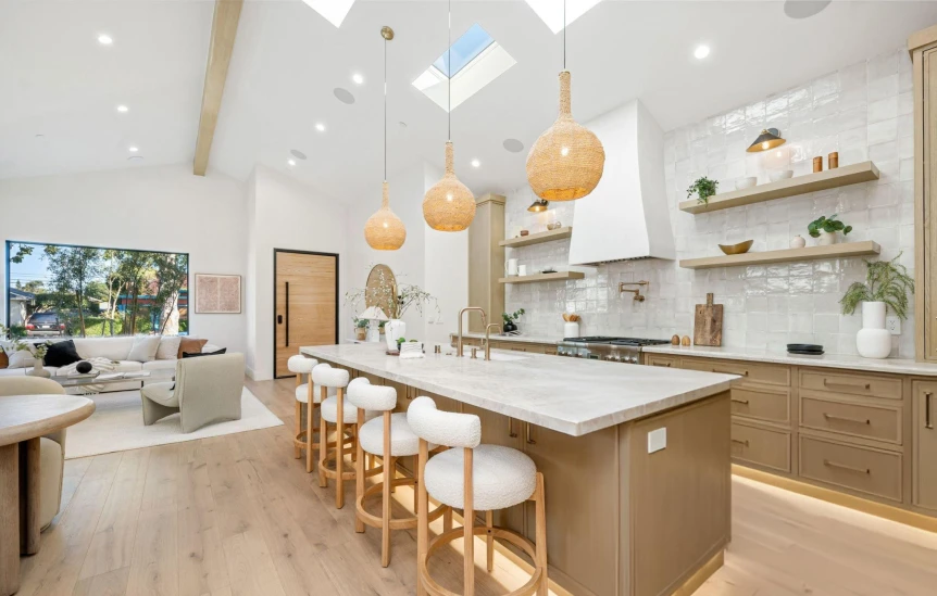 Modern open concept kitchen and living room with white walls, wood cabinetry, and vaulted ceiling