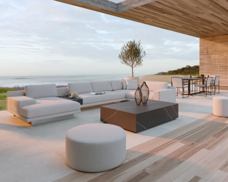 Modern outdoor living space with minimalist furniture, wooden deck, and seamless ocean views under covered patio