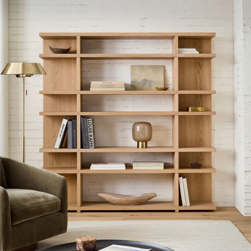 Modern Japandi-style wooden bookshelf with asymmetrical shelves displaying minimalist decor and books in neutral living room