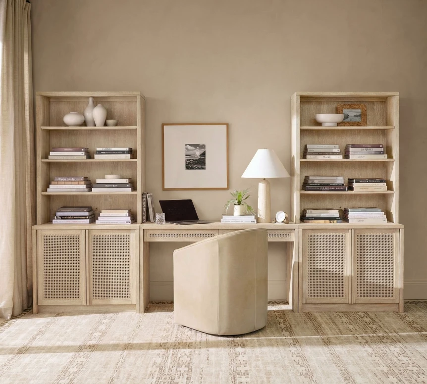 Modern home office with a beige cane fronted credenza, two narrow bookcases, a curved light wood desk, and a neutral minimalist palette