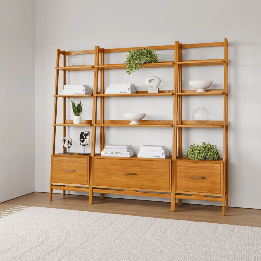 Three-section ladder bookshelf in natural wood with drawers, styled with plants, books, and white decorative items