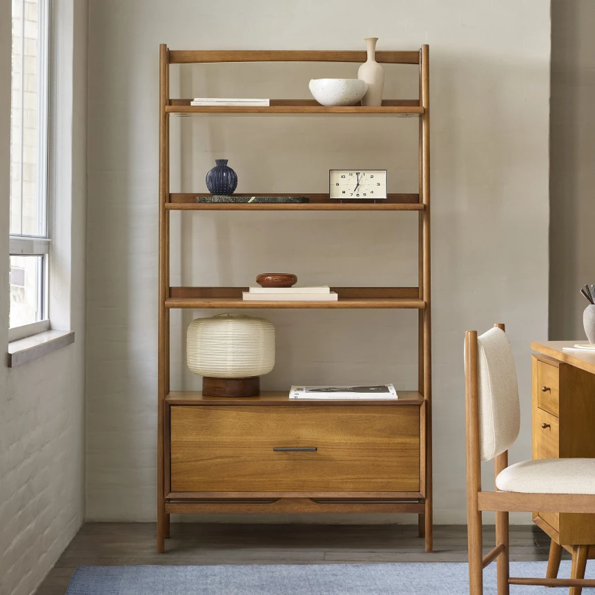 Modern wooden bookshelf with open shelving and bottom drawer displaying minimalist decor and books